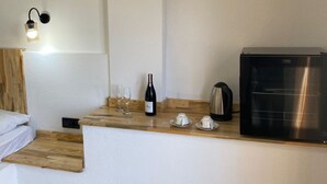 Una cocina compacta con encimera de madera, una botella de vino, copas, un hervidor y una cafetera.