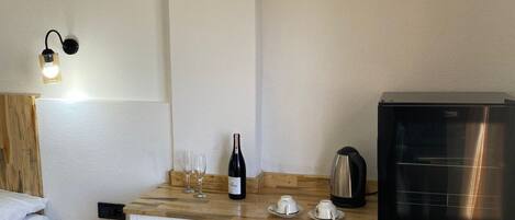 Una cocina compacta con encimera de madera, una botella de vino, copas, un hervidor y una cafetera.