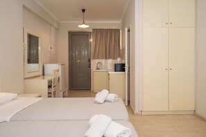 Hotellihuone, jossa on sänky, työpöytä, tuoli, pieni keittiö ja vaatekaappi.