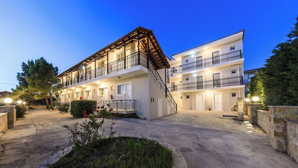 A two-story hotel with a central staircase, balconies, and a well-lit entrance. - Karras Livin (Zakynthos)