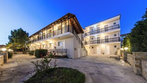 A two-story hotel with a central staircase, balconies, and a well-lit entrance. - Karras Livin (Zakynthos)