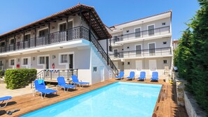 A hotel with a swimming pool, blue lounge chairs, and a wooden deck. - Karras Livin (Zakynthos)