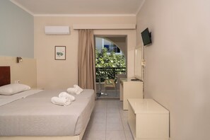 A hotel room with a bed, a desk, a chair, a TV, and a balcony with a view. - Karras Livin (Zakynthos)