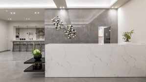 Una moderna recepción con mostrador de mármol, una obra de arte decorativa y una planta en maceta.