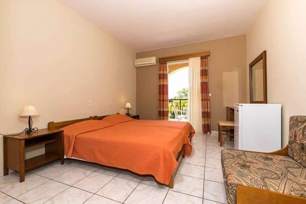 A hotel room with a bed, a desk, a chair, and a refrigerator.