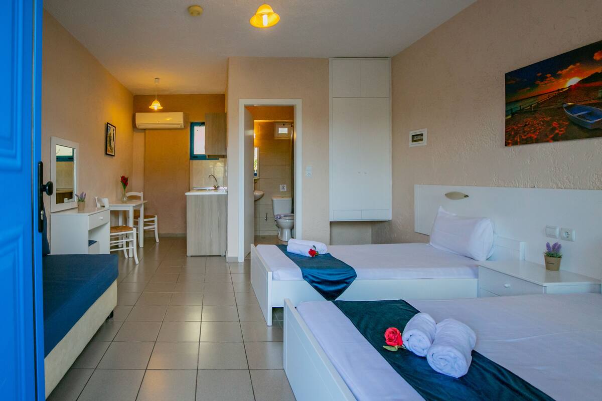 Ein Hotelzimmer mit zwei Betten, einem Schreibtisch und einem durchgegangenen Tür sichtbaren Badezimmer.