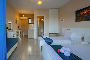 A hotel room with two beds, a desk, and a bathroom visible through an open door.