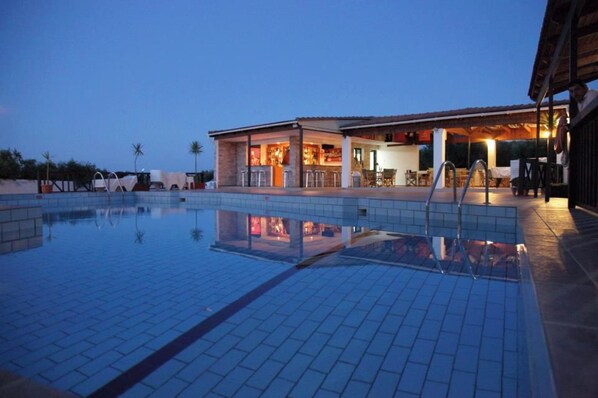 A swimming pool with a bar area and outdoor seating.