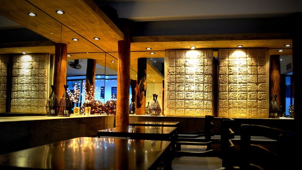 A dimly lit restaurant with wooden beams and a long table. - Hotel Maya Rue (Palenque)