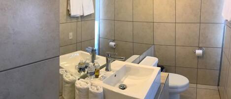 Un baño moderno con un lavamanos grande, inodoro y perchero para toallas.