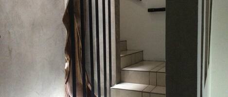 Una escalera con barandilla y una puerta que da a otra habitación.