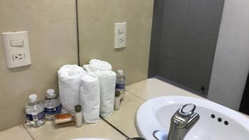 Un baño con dos lavamanos, toallas, artículos de aseo y un espejo.