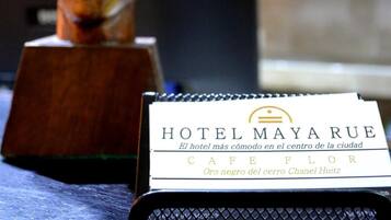 Een receptiebalie van een hotel met een houten buste beeldhouwwerk en een bordje met HOTEL MAYARUE erop.