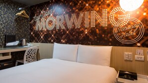 Una habitación de hotel con cama, escritorio y una pared con texto iluminado.