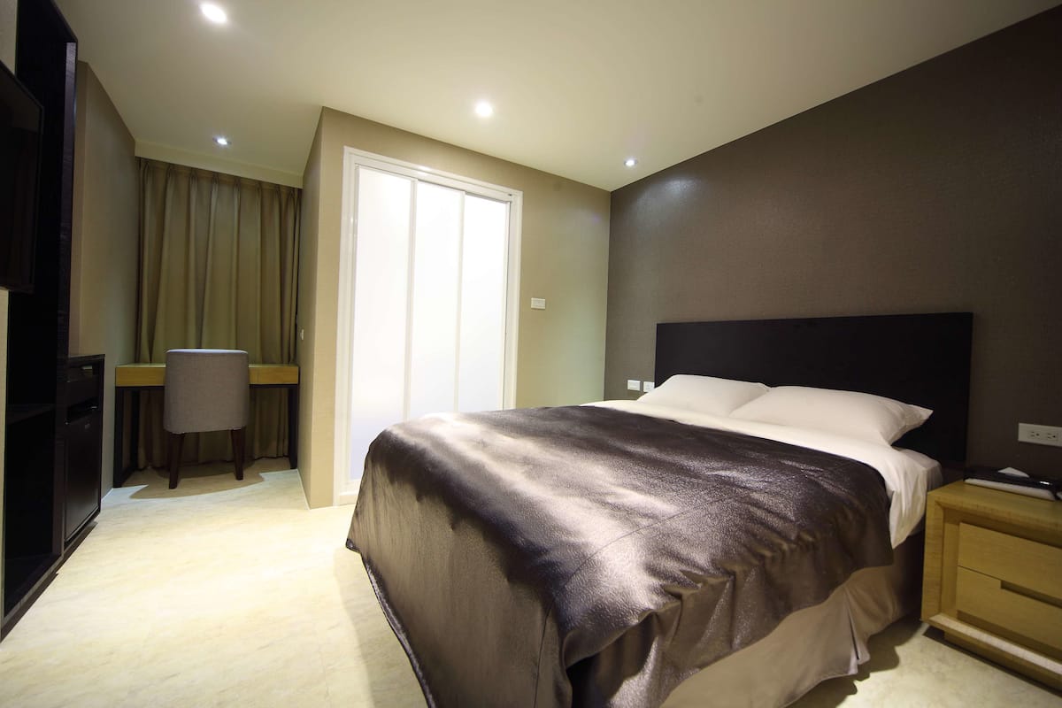 A hotel room with a bed, a desk, and a chair.