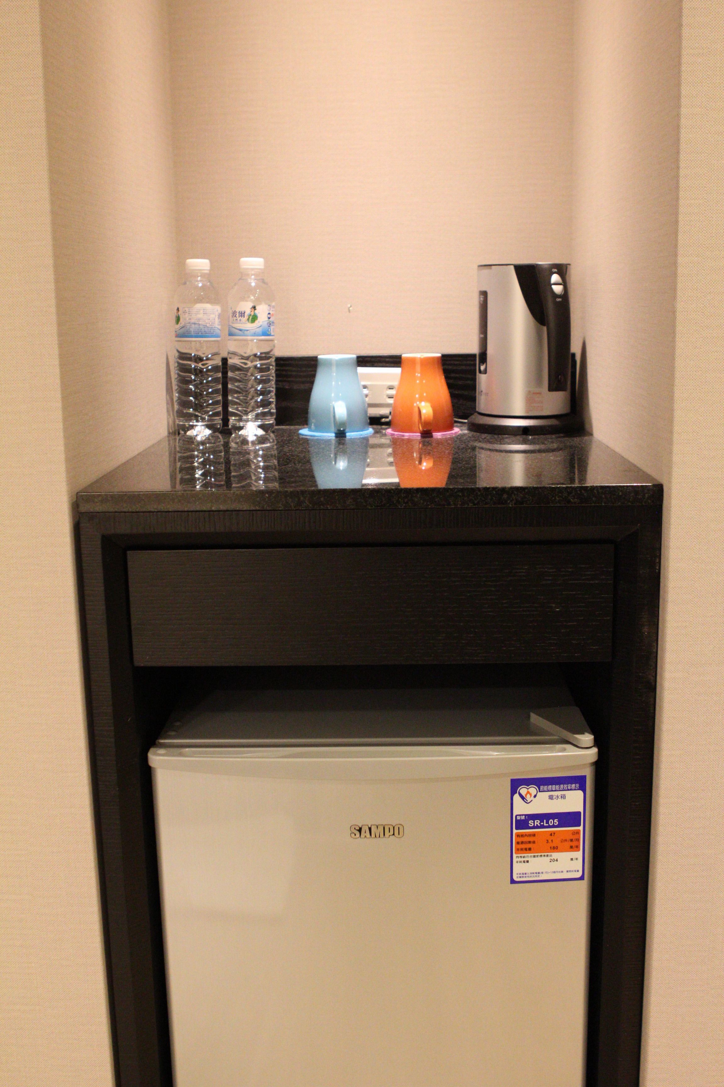 Eine Minibar mit einem Kühlschrank, einer Kaffeemaschine und zwei Wasserflaschen.