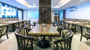 A restaurant with a central marble pillar, patterned chairs, and tables. - Hotel Kosala (Vijayawada)