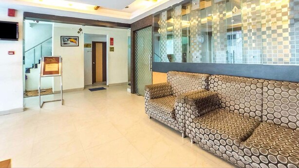 A reception area with a patterned sofa, a staircase, and a glass wall with a geometric pattern. - Hotel Kosala (Vijayawada)