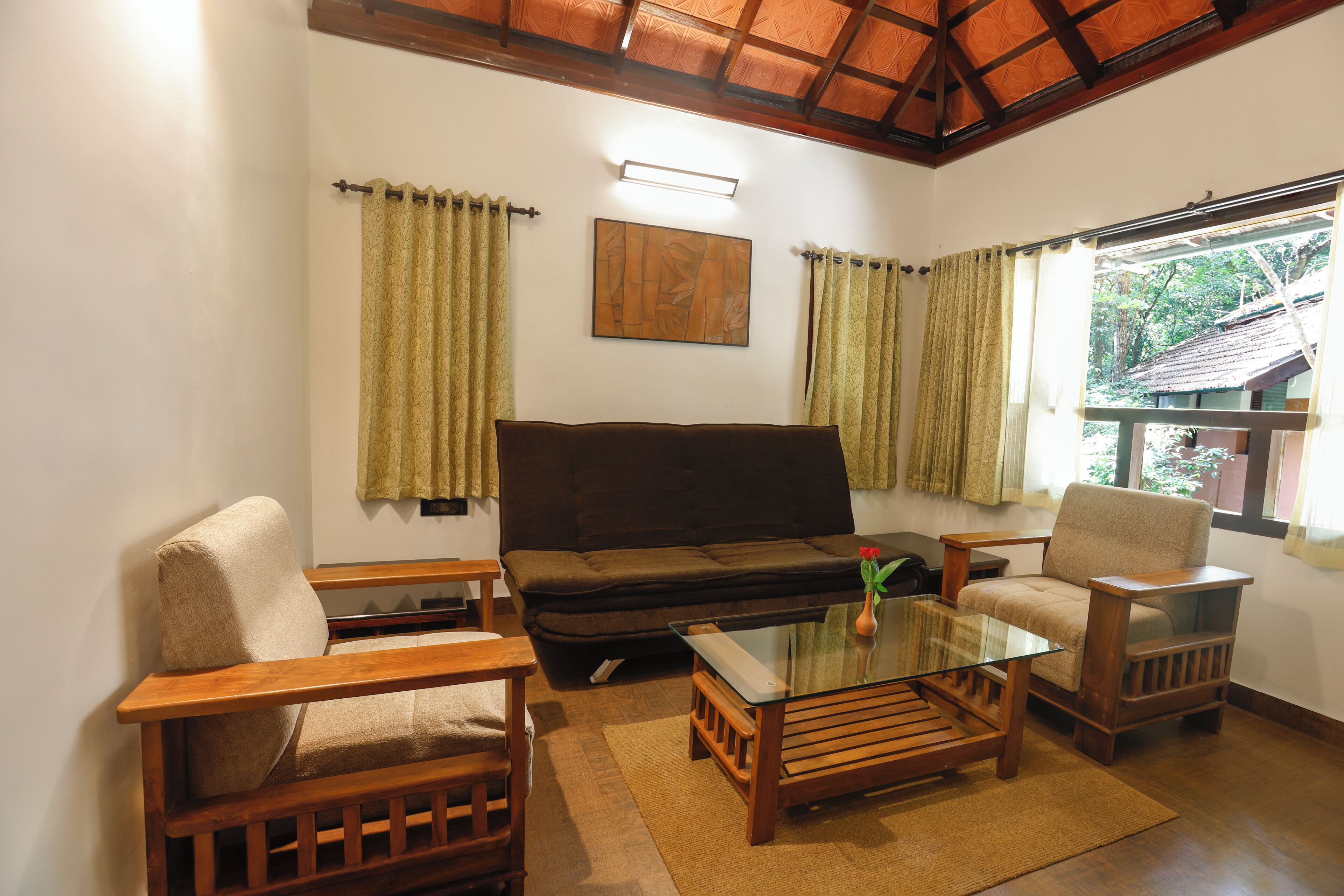 A living room with a sofa, two armchairs, a glass coffee table, and curtains.
