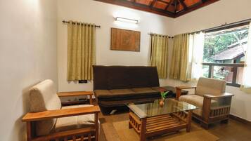 A living room with a sofa, two armchairs, a glass coffee table, and curtains.