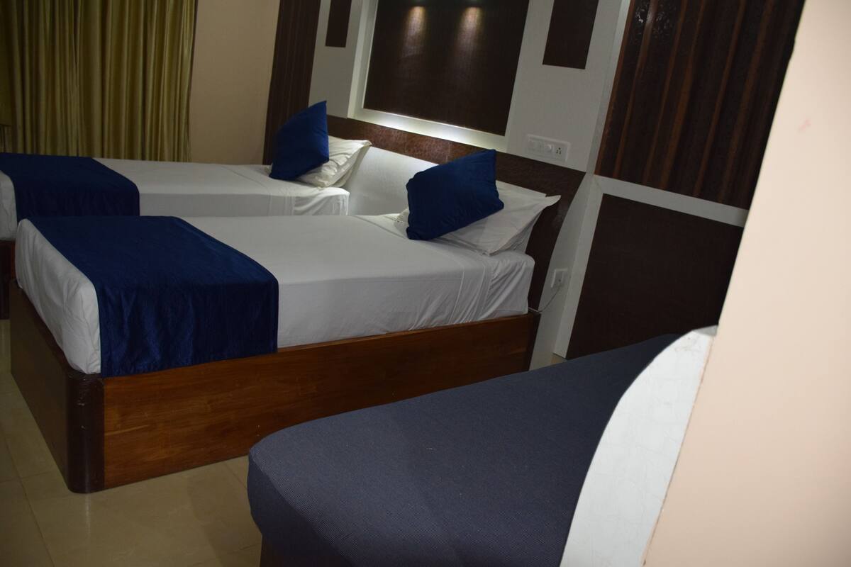 Habitación de hotel con dos camas individuales, cada una con cubrecama y almohada azules, y cabecero de madera.
