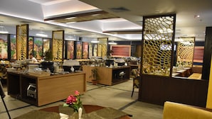 A hotel lobby with a reception desk, seating areas, decorative screens, and a large informational display. - Hotel Pushpak (Bhubaneshwar)