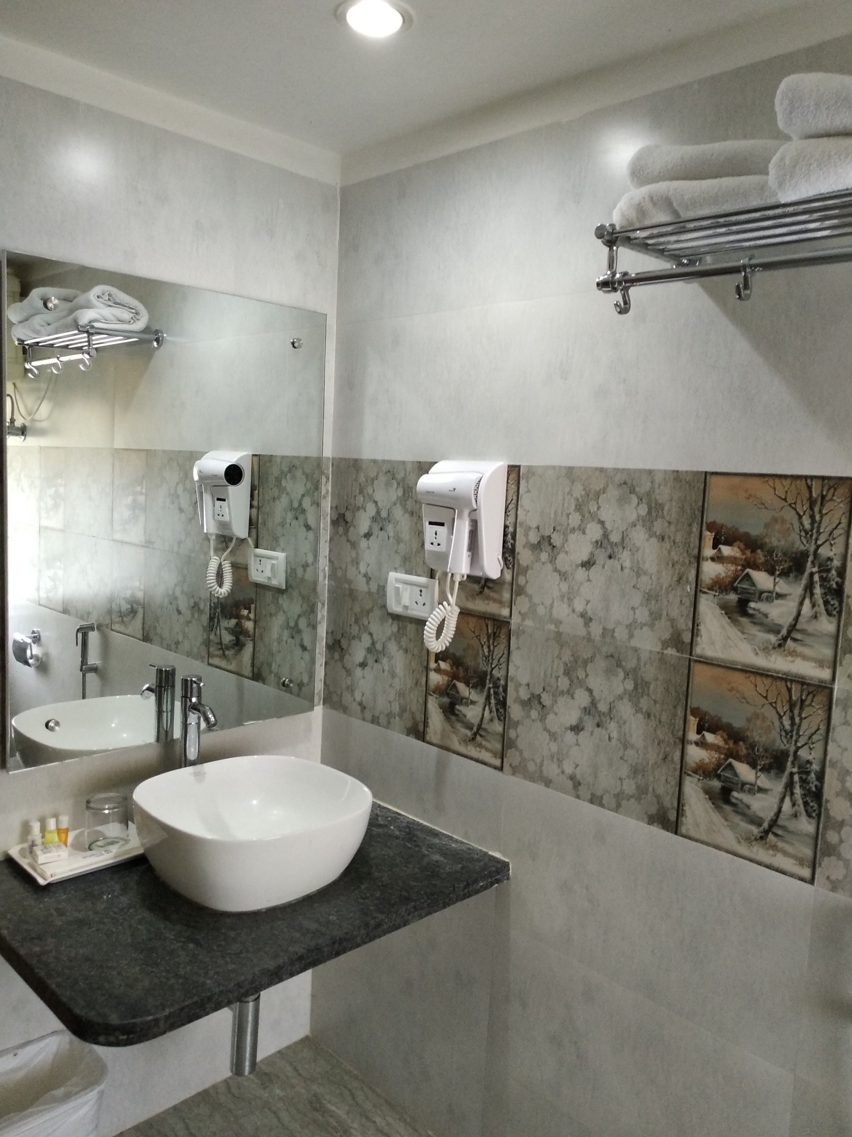 A modern bathroom with a large sink, a mirror, and a towel rack.
