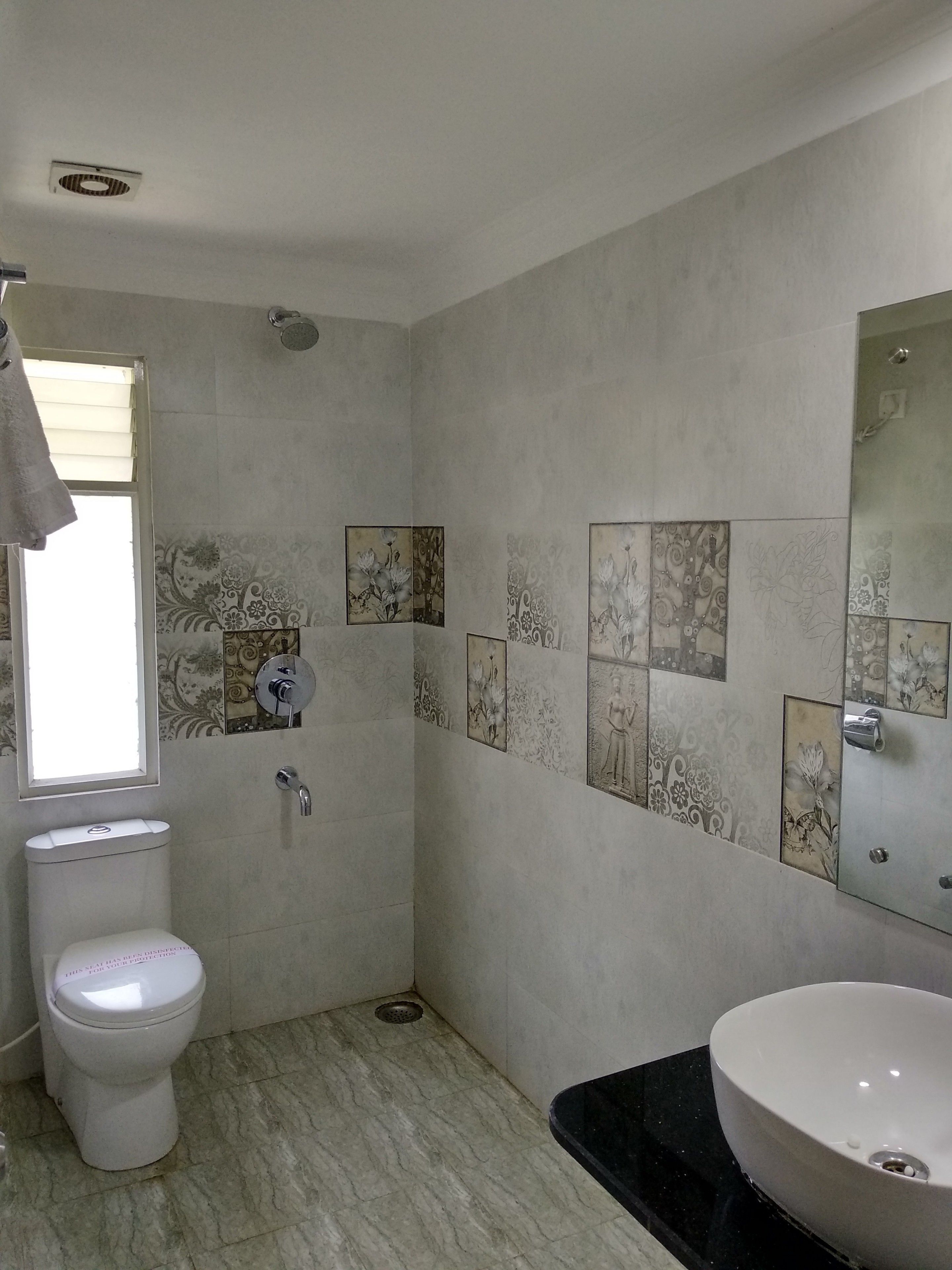 A bathroom with a toilet, sink, shower, and decorative tiles.