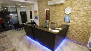 A reception desk with a clock, a framed quote, and a poster on the wall. - Hotel Yog Vashishth (Yamkeshwar)