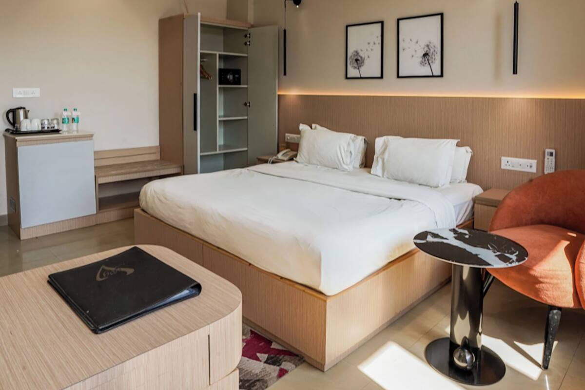 A modern hotel room with a bed, desk, chair, wardrobe, and a ceiling fan.