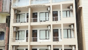 A multi-story hotel with balconies and air conditioning units. - Hotel Yog Vashishth (Yamkeshwar)