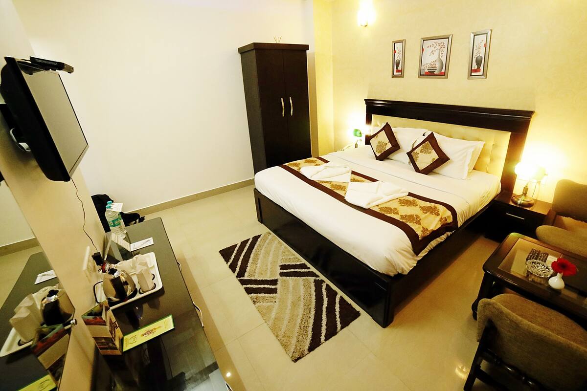 A hotel room with a bed, a desk, a chair, a wardrobe, and a TV.