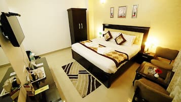Una habitación de hotel con una cama, un escritorio, una silla, un armario y un televisor.