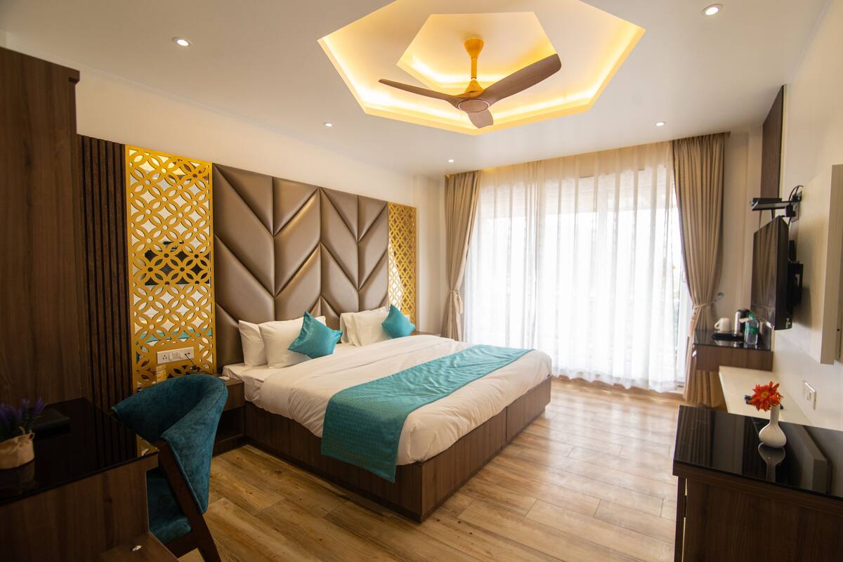 A modern bedroom with a large bed, a ceiling fan, a wooden floor, and a decorative wall panel.