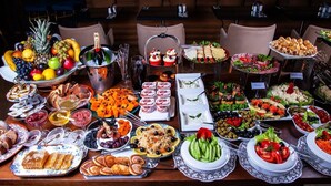 A buffet table with various food items and a bottle of champagne. - Hotel Grand Shiva (Haridwar)
