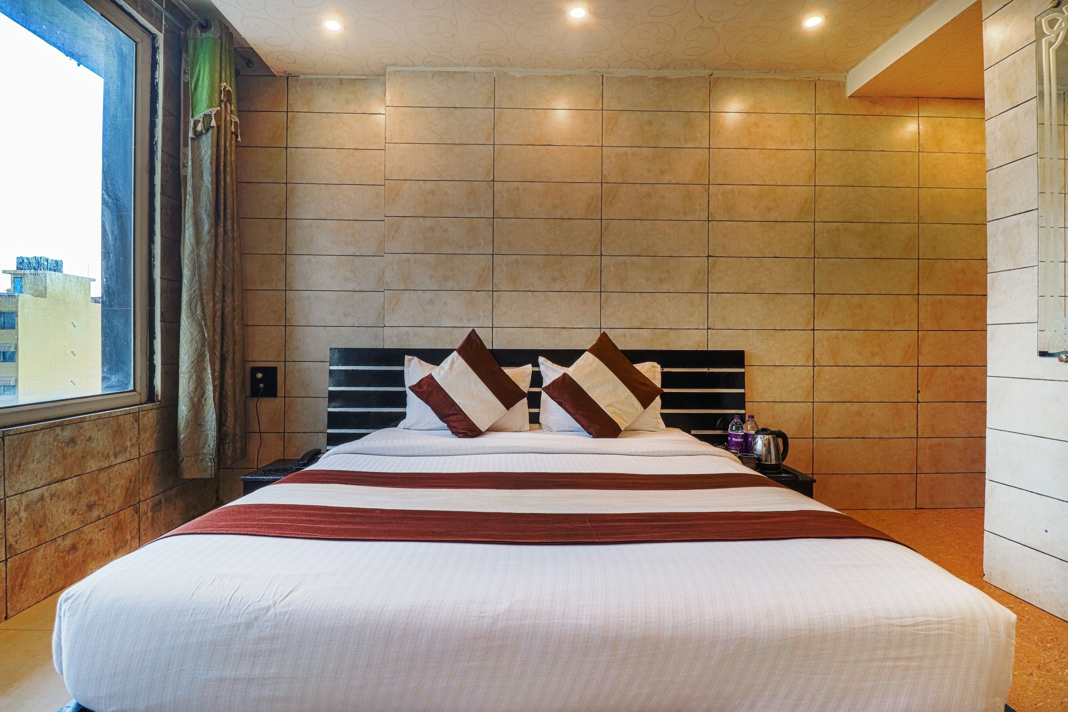 A hotel room with a large bed, a headboard, and a window with curtains.