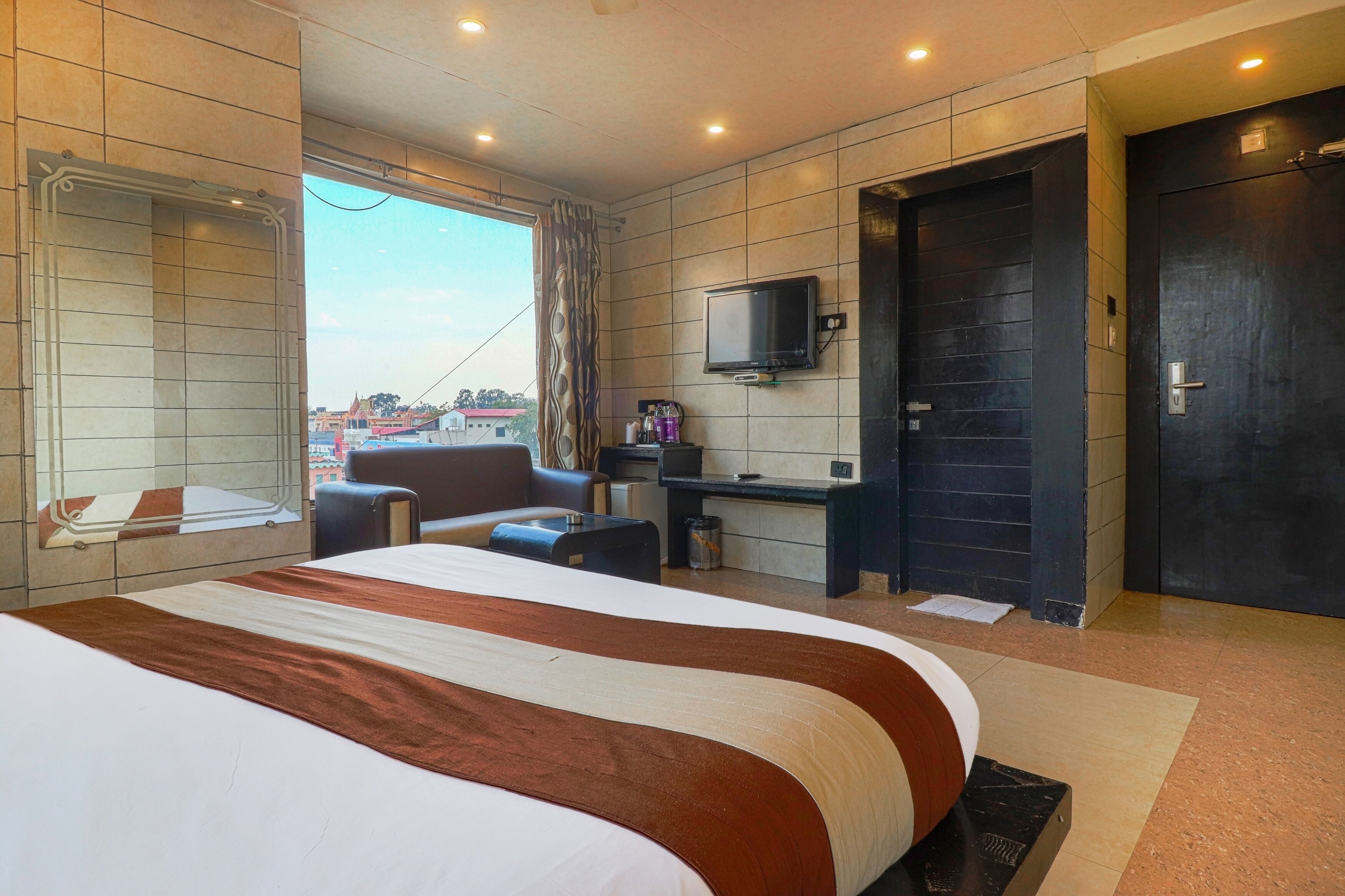 Een hotelkamer met een groot bed, een bureau, een stoel, een televisie en uitzicht op de stad.