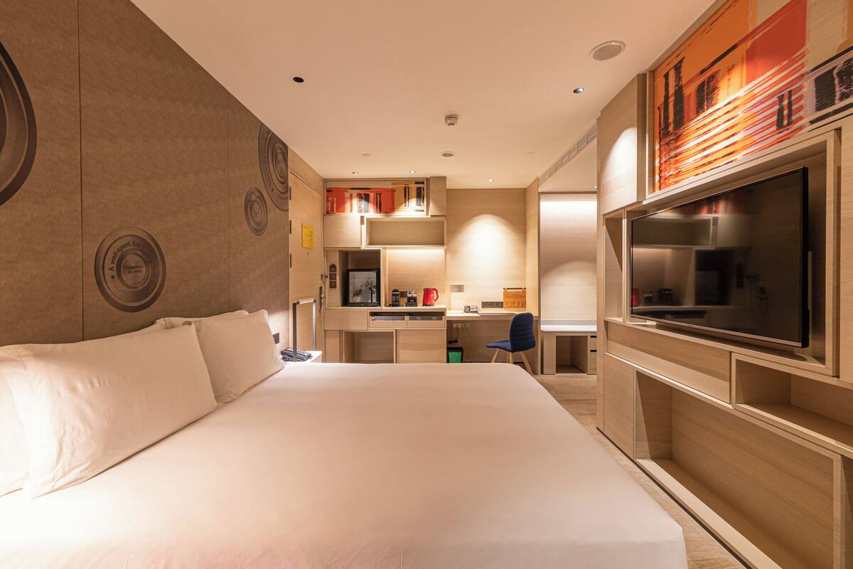Une chambre d’hôtel avec un grand lit, un bureau avec une chaise, une télévision et un coin cuisine.
