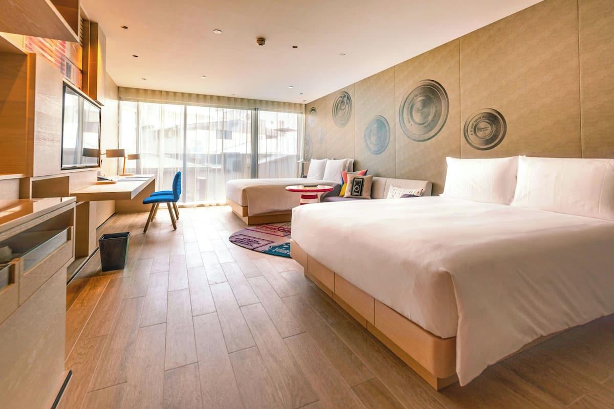 Une chambre d’hôtel moderne avec un grand lit, un bureau, une chaise et une grande fenêtre.