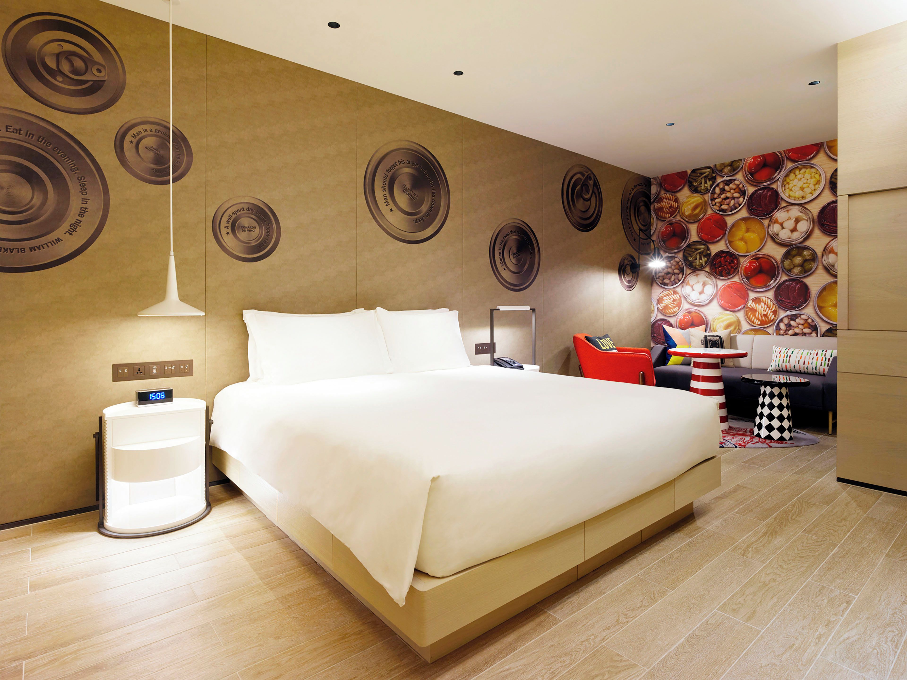 A modern hotel room with a large bed, a bedside table, a lamp, a wall clock, and a wall with circular patterns.