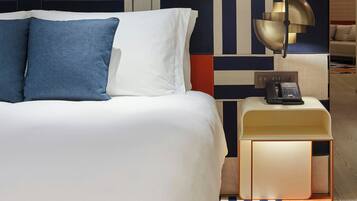 Ein Hotelzimmer mit einem Bett, einem Nachttisch mit Telefon und einer Wand mit geometrischem Muster.