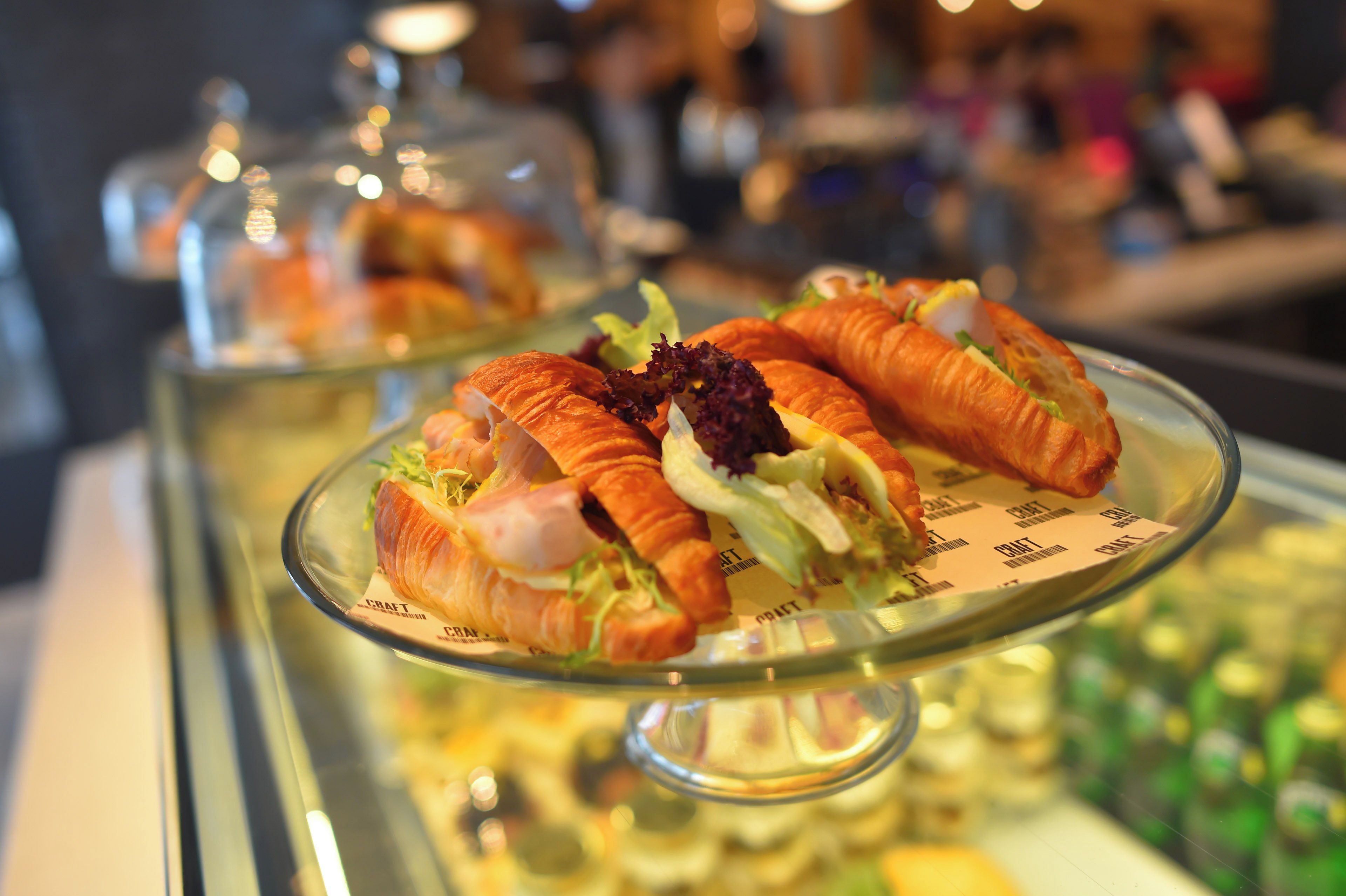 A display case with sandwiches and a glass dome covering a dish.