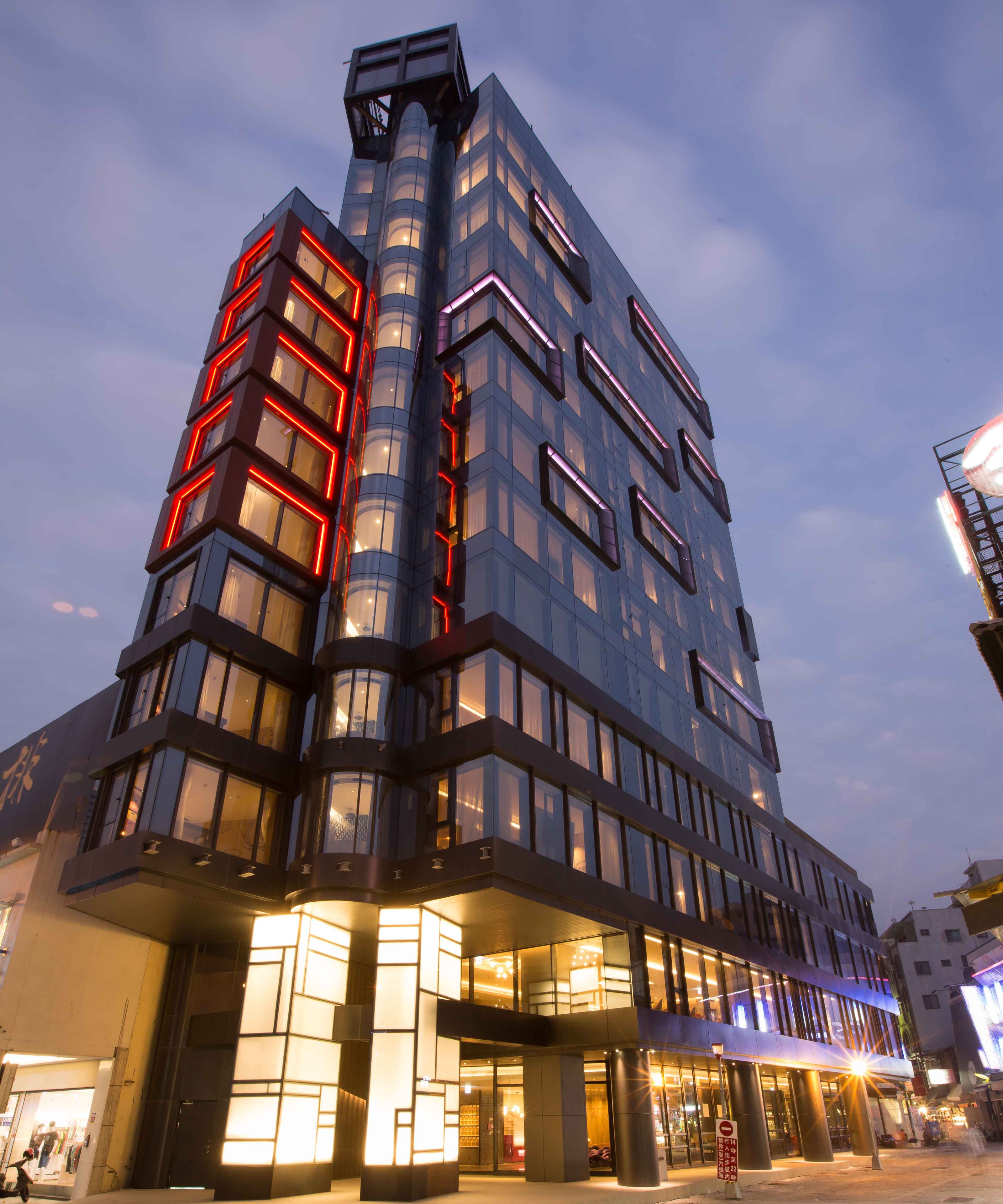 Een modern gebouw met meerdere verdiepingen, grote ramen en een opvallende hoekopstand.