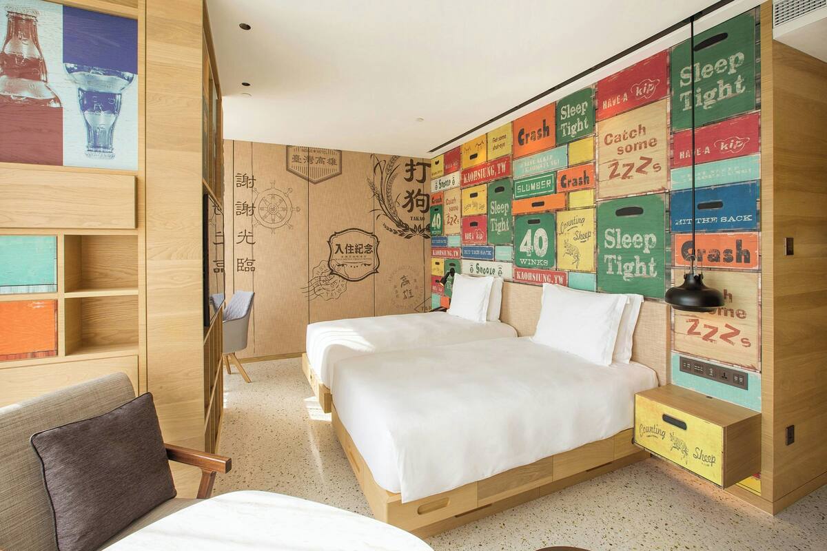 Une chambre à coucher comprenant un lit, une chaise et un mur décoré d’enseignes de style rétro.