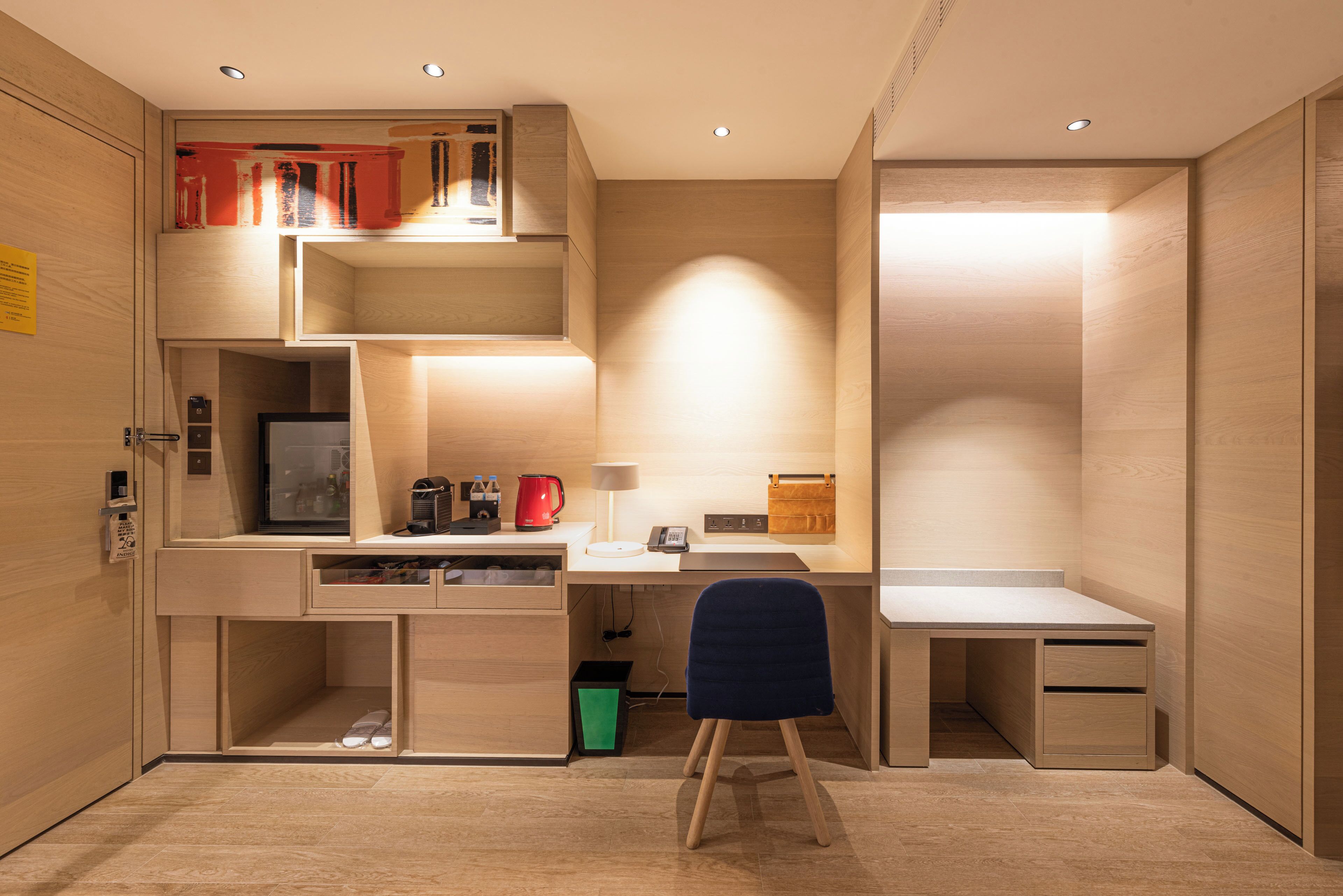 A compact room with a desk, chair, and built-in shelving.
