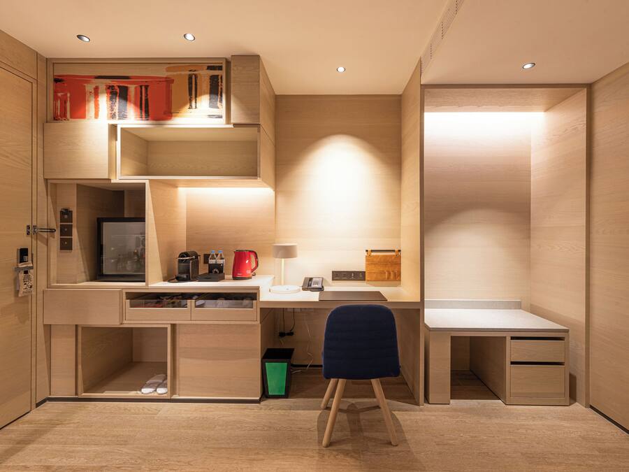 A compact room with a desk, chair, and built-in shelving.