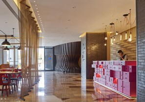 A modern hotel lobby with a reception desk, seating area, and decorative lighting. - Hotel Indigo Kaohsiung Central Park by IHG (Kaohsiung)