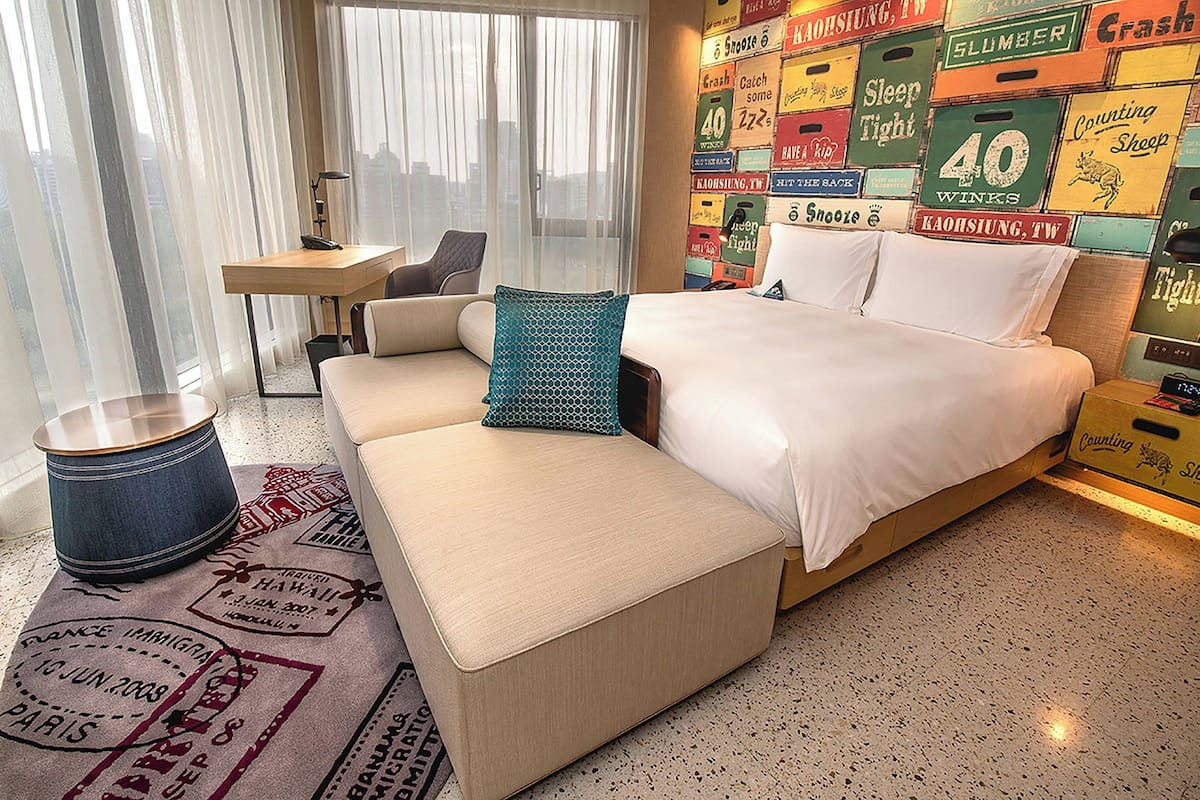 Une chambre d’hôtel avec un lit, un canapé, un bureau et une grande fenêtre.