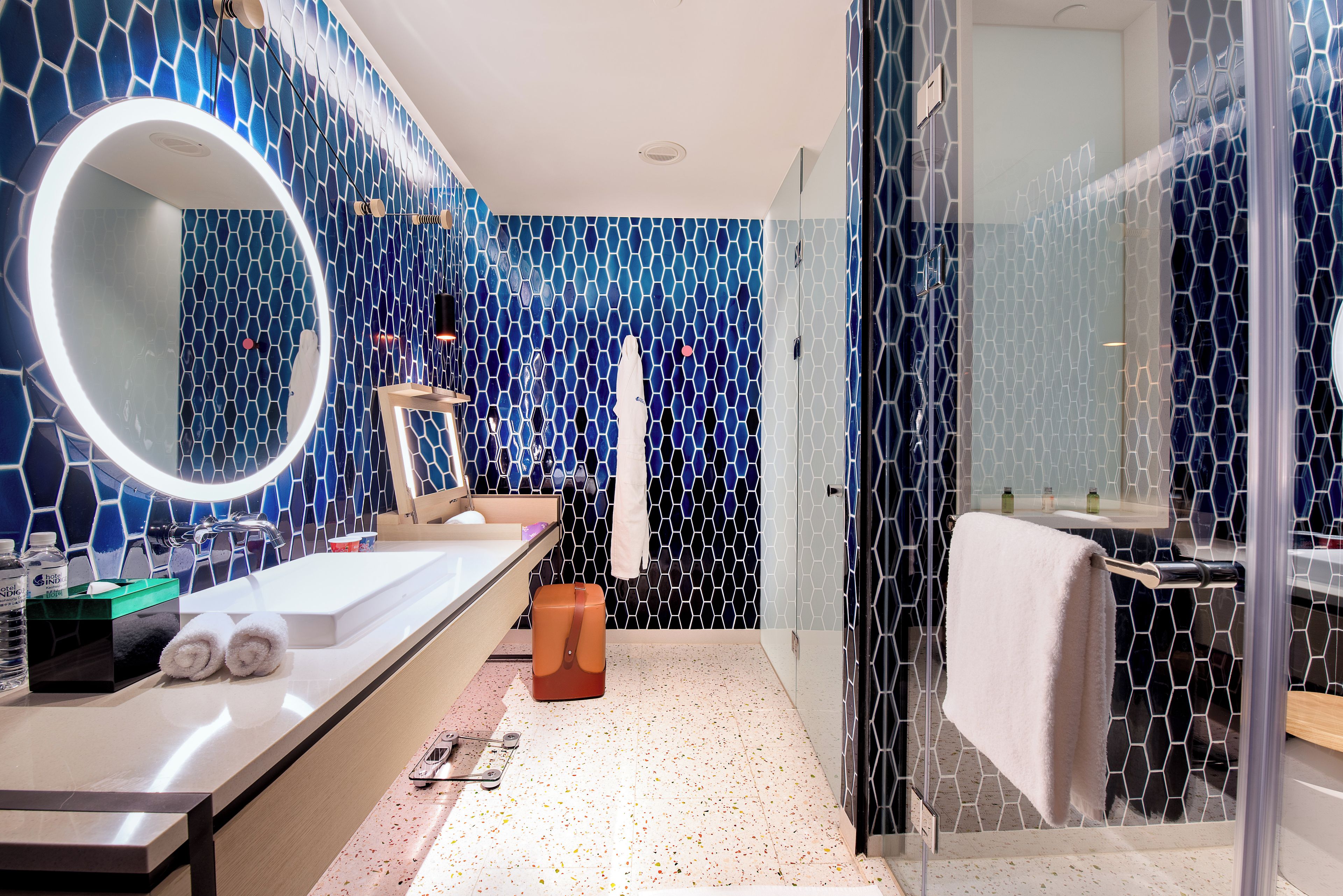 Un baño moderno con un espejo grande, un lavamanos y una zona de ducha.