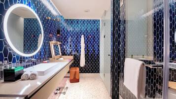 Un baño moderno con un espejo grande, un lavamanos y una zona de ducha.